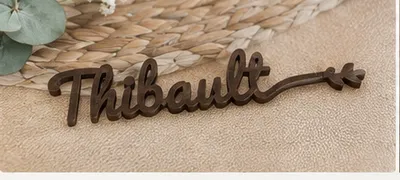 Marque-place « Thibault » sans date, en brun bois, posé sur un set tressé.