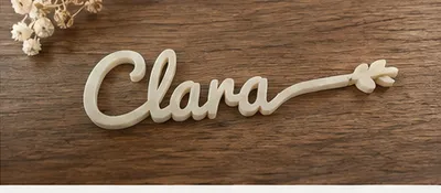 Marque-place « Clara » sans date, en beige, posé sur un plateau de bois foncé.